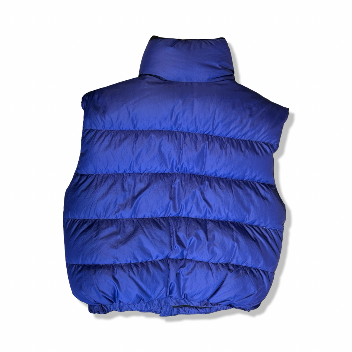 Back view of a purple quilted down vest against a white background.