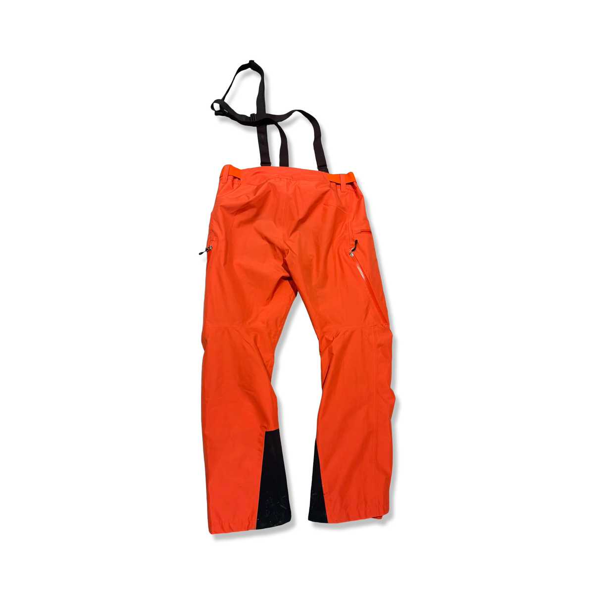 Baksidan av ett par orange skalbyxor Bergans Stranda 2L för dam med svarta hängslen, fotograferade mot en vit bakgrund.