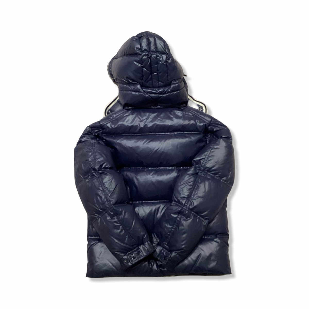 Baksidan av en blå dunjacka från Moncler med huva, fotograferad mot en vit bakgrund.