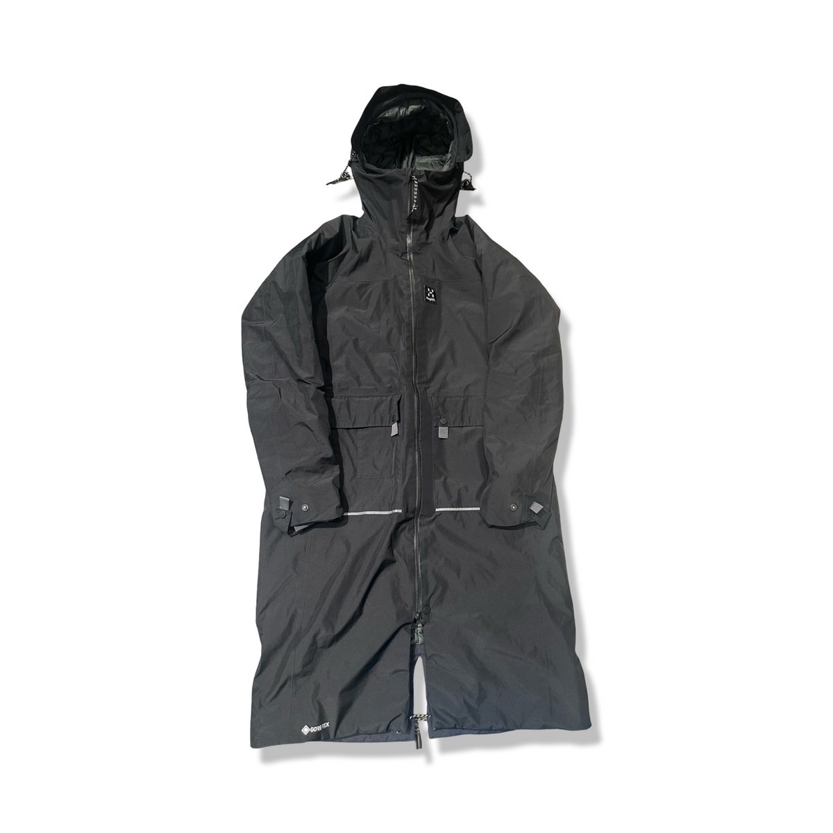 Svart Haglöfs parkas för dam i lång modell med huva, fotograferad framifrån mot en vit bakgrund.