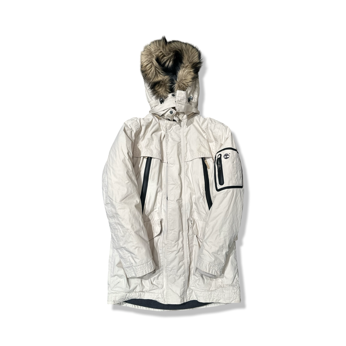 Beige parkas från Timberland för dam med huva och fuskpäls, fotograferad framifrån mot en vit bakgrund.