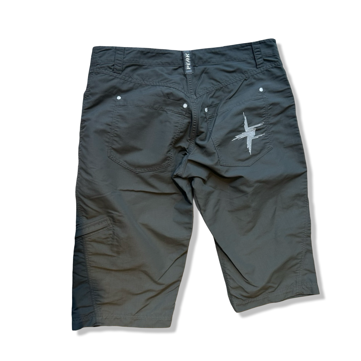 Gröna shorts från Peak Performance modell 3xdry i dammodell M, fotograferade bakifrån mot vit bakgrund.