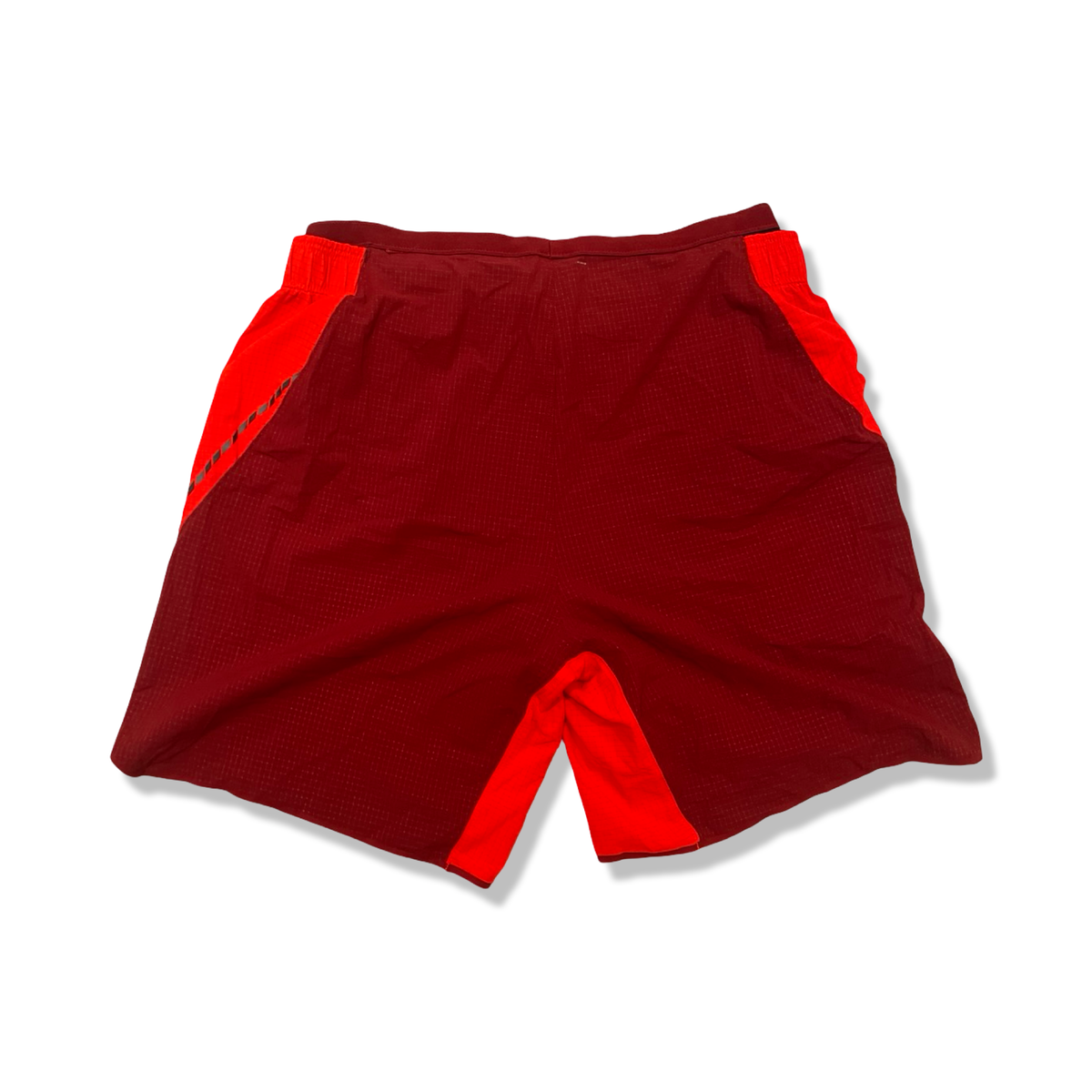 Baksidan av röda träningsshorts från Salomon för dam, fotograferade mot en vit bakgrund.