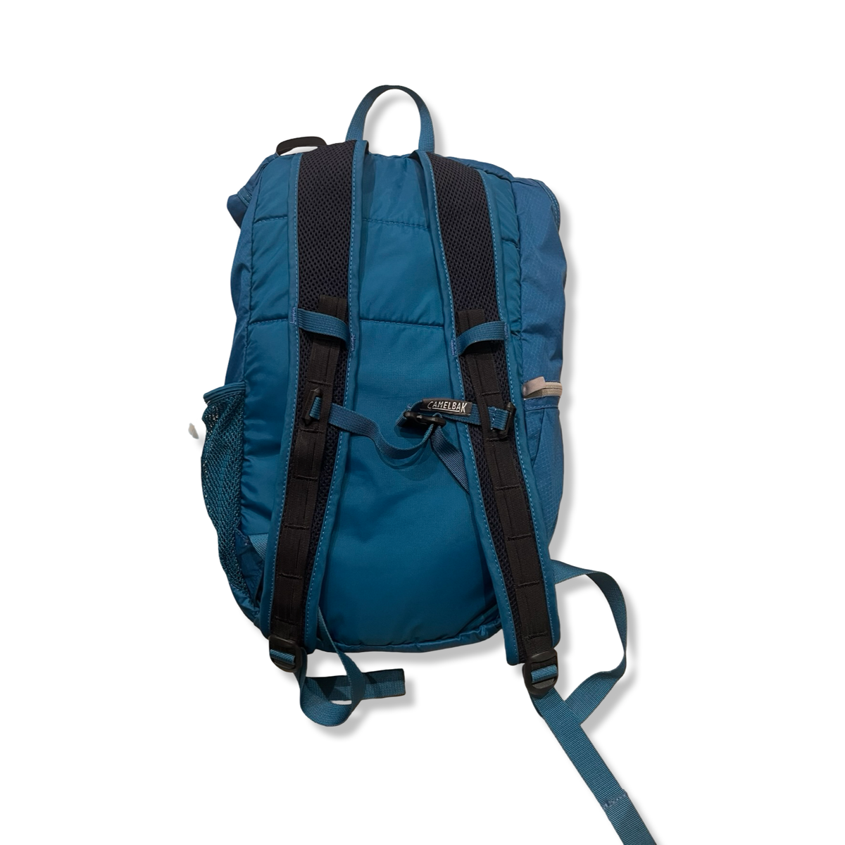 Baksidan av en blå ryggsäck från Camelbak Arete 18 med svarta axelremmar, fotograferad mot en vit bakgrund.