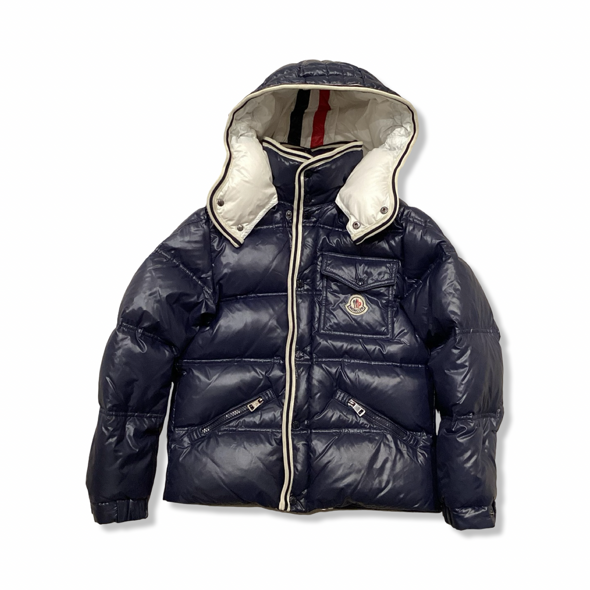 Blå dunjacka för barn från Moncler med luva, fotograferad framifrån mot en vit bakgrund.