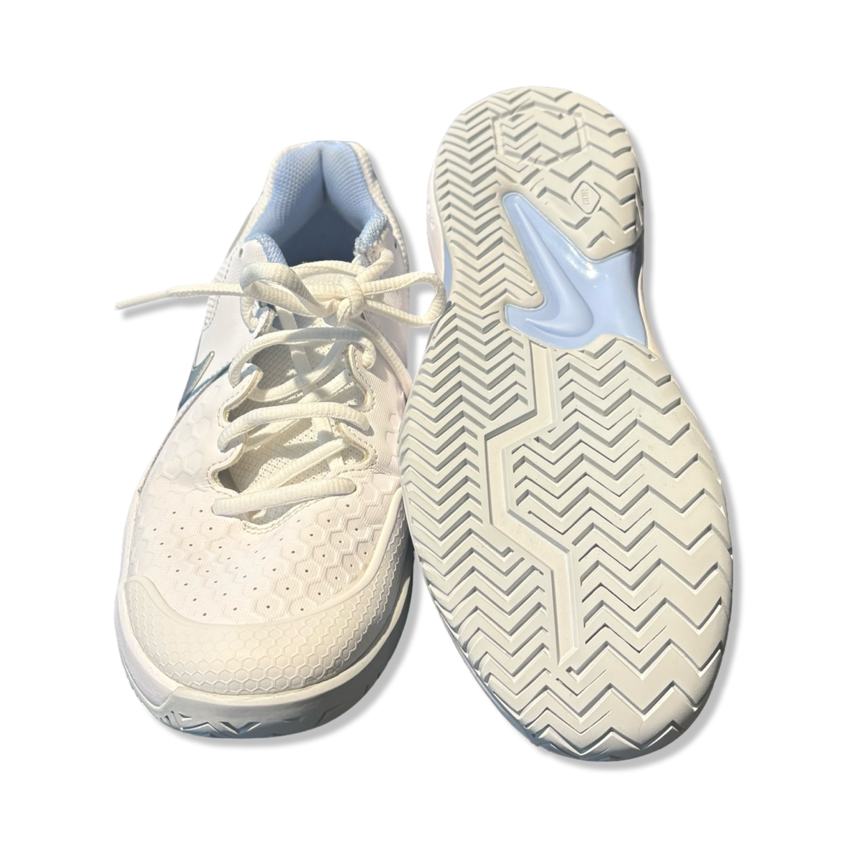 White women's Nike running shoes with laces and patterned outsoles, front and bottom view on white background.