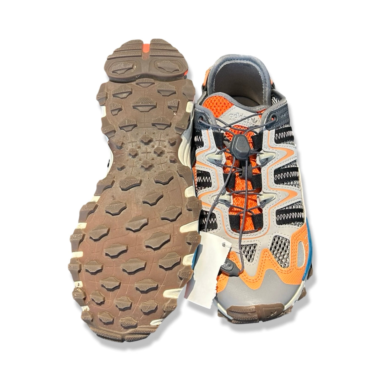 Adidas träningsskor för dam i orange, grått och blått med grov sula och snabbsnörning mot vit bakgrund.