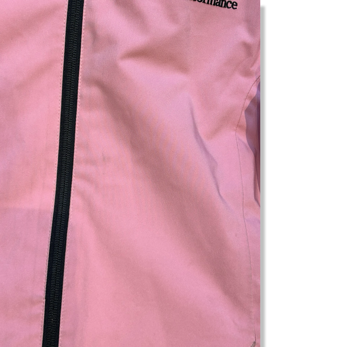 Close-up of a pink kids' Peak Performance ski jacket with a black zipper, showing the material's condition.