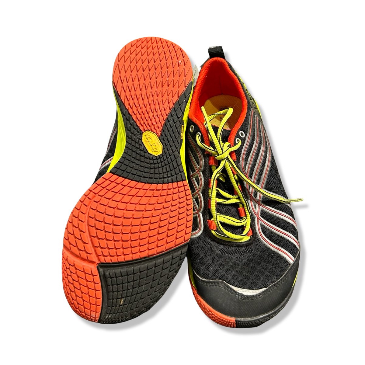 Black Merrell training shoes with orange outsole and yellow shoelaces, photographed from underneath and front against a white background.