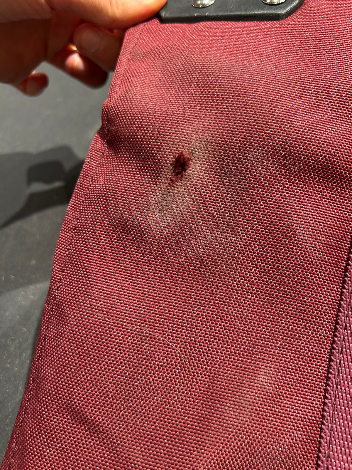 Närbild på ett litet hål på baksidan av det vinröda Douchebag-skidfodralet.