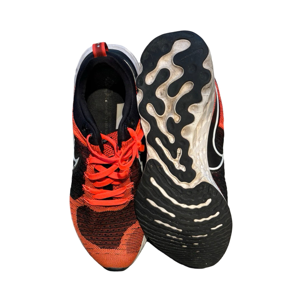 Nike löparskor för herr i orange och svart, fotograferade uppifrån och med sulan synlig mot en vit bakgrund.