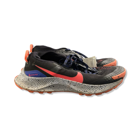 Svart damlöparsko Nike Pegasus Trail Gore-Tex med orangea och blå detaljer samt stänkmönstrad sula, fotograferad från sidan mot vit bakgrund.