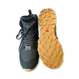 Black Salomon Outsnap CSWP hiking boots with a patterned rubber sole, shown from the front and with the sole facing upwards against a white background.