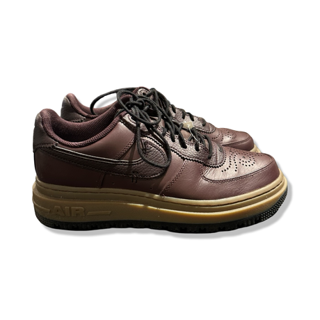 A pair of brown leather Nike Air Force 1 Luxe women's sneakers, photographed from the side against a white background.