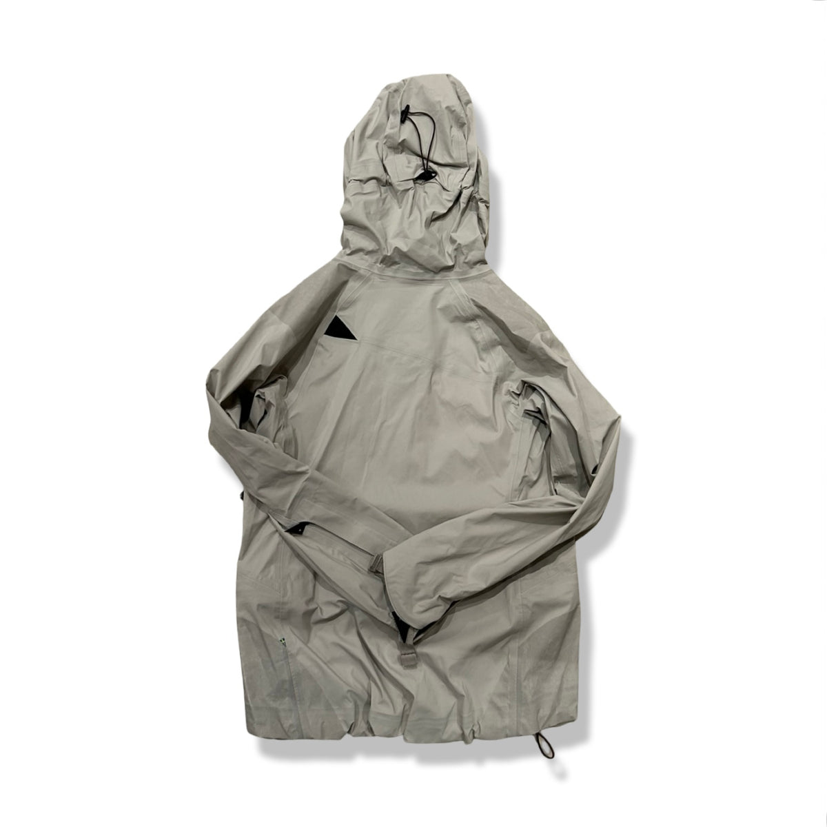 Back view of a beige and grey Klättermusen women's hooded down jacket against a white background.