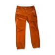 Orange regnbyxor Houdini BFF Pants för dam med dragkedjor, fotograferade framifrån mot en vit bakgrund.