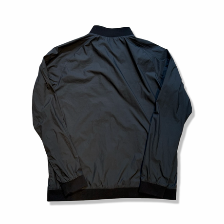 Baksidan av en svart träningsjacka från Peak Performance modell G Octon Jacket, fotograferad mot en vit bakgrund.