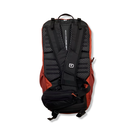 Baksidan av en orange Ortovox Traverse 20 unisex-ryggsäck med vadderat bärsystem, fotograferad mot vit bakgrund.