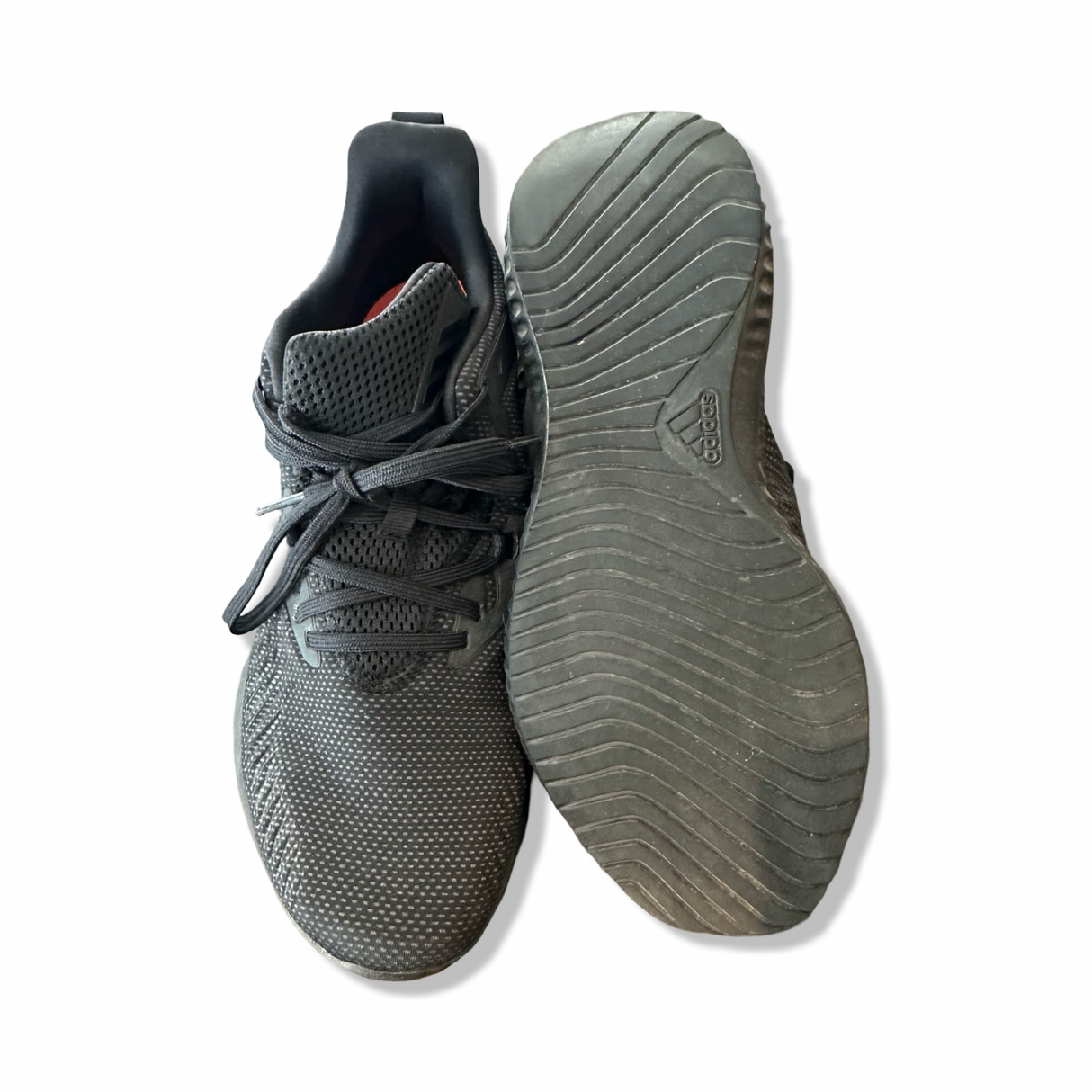 Svarta löparskor från Adidas med ovansida i meshtyg och mönstrad gummisula, fotograferade uppifrån mot vit bakgrund.