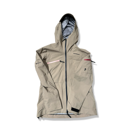 Beige skaljacka Peak Performance W Alpine Gore-Tex jacket med huva, fotograferad framifrån mot en vit bakgrund.