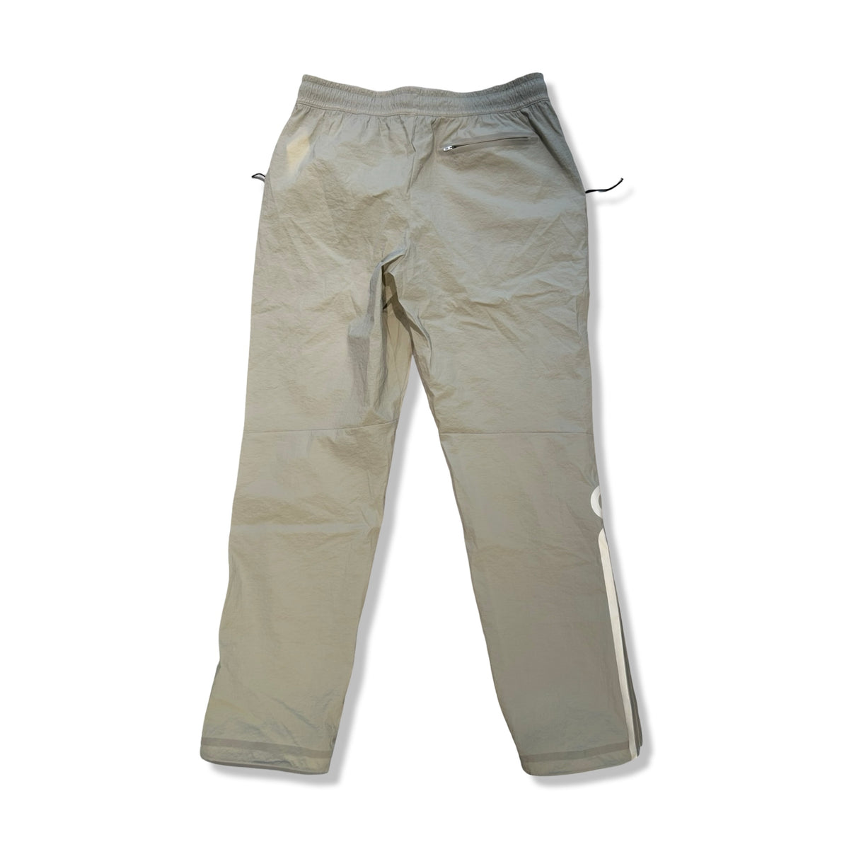 Baksidan av ett par beige funktionsbyxor ON Track Pants IKON för herr med dragkedja bak, fotograferade mot en vit bakgrund.