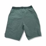 Baksidan av ett par gröna Salomon Wayfarer Pull On Short funktionsshorts för herr, fotograferade mot en vit bakgrund.