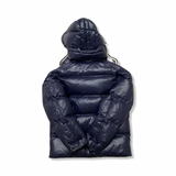 Baksidan av en blå dunjacka från Moncler med huva, fotograferad mot en vit bakgrund.