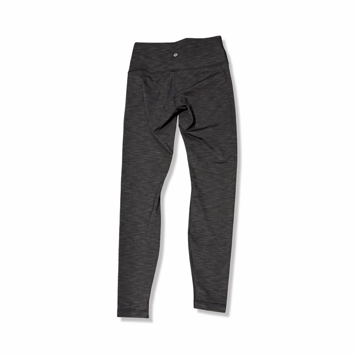 Baksidan av grå träningstights från Lululemon för dam, fotograferade mot en vit bakgrund.