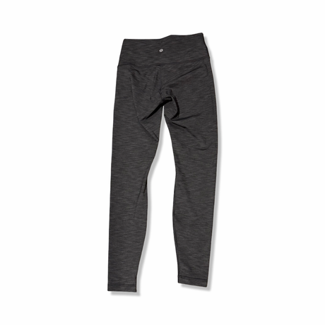 Baksidan av grå träningstights från Lululemon för dam, fotograferade mot en vit bakgrund.