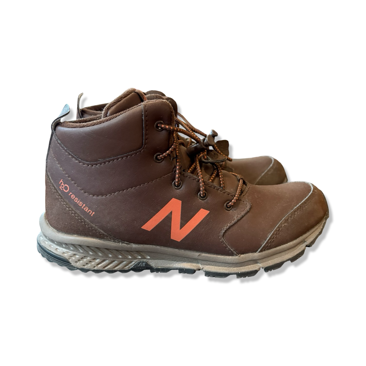 Ett par bruna vandringskängor från New Balance för barn i storlek 35,5, fotograferade från sidan mot en vit bakgrund.