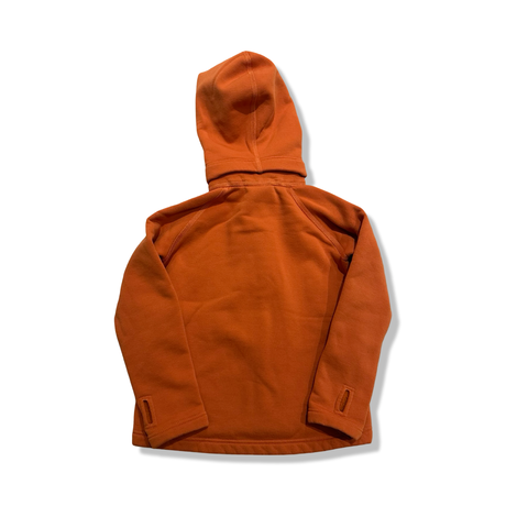 Baksidan av en orange Houdini Power Houdi fleececardigan för barn, fotograferad mot en vit bakgrund.