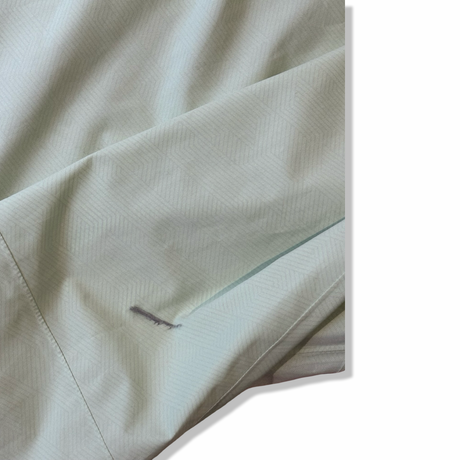 Close-up of a stain on the sleeve of a green women's shell jacket from Peak Performance.