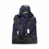 Baksidan av en blå Helly Hansen seglarjacka för dam med huva och reflexdetaljer, fotograferad mot en vit bakgrund.