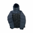 Black Marmot women's down jacket with hood and chest pockets, front view against a white background.