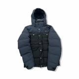 Black Marmot women's down jacket with hood and chest pockets, front view against a white background.