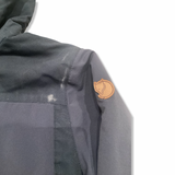 Close-up of the sleeve and shoulder of a blue Fjällräven rain jacket with a leather logo.
