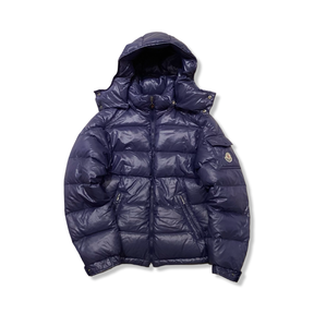 Blå dunjacka från Moncler med huva för barn, fotograferad framifrån mot en vit bakgrund.