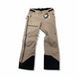 Beige skalbyxor från Peak Performance M Alpine Gore-Tex Pants för herr med svarta förstärkningar, fotograferade framifrån mot en vit bakgrund.