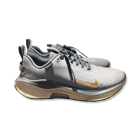 Grå löparskor Nike Infinity 4 GTX Unisex med gulddetaljer, fotograferade från sidan mot vit bakgrund.