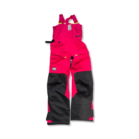 Rosa och svarta seglarbyxor från Helly Hansen i W Skagen Offshore Bib-modell för dam, visade mot vit bakgrund.
