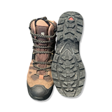 Brown Salomon QUEST 4 GORE-TEX men's boots, shown from the front with focus on the lugged outsole, against a white background.