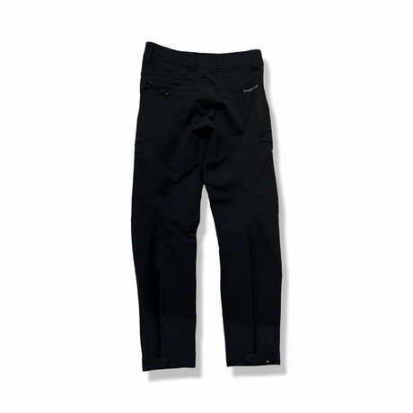 Baksidan av ett par svarta Norröna svalbard flex pants för dam, fotograferade mot en vit bakgrund.