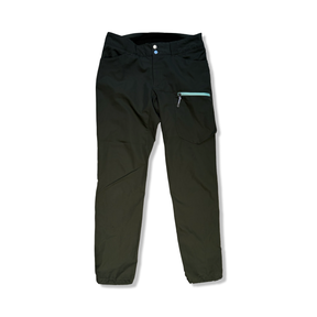 Green Houdini women's hiking pants featuring a zippered pocket, front view against a white background.
