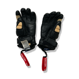 A pair of black Hestra gloves with red straps and beige details, photographed against a white background.