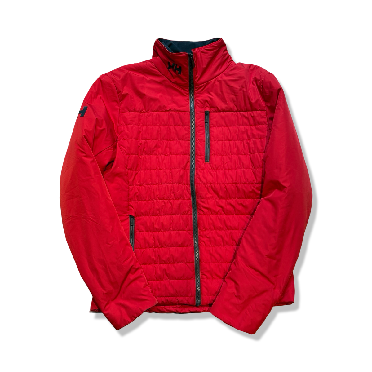 Röd syntetjacka från Helly Hansen för dam med dragkedja och bröstficka, fotograferad framifrån mot en vit bakgrund.