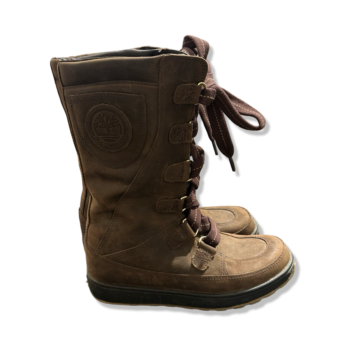 Ett par bruna vinterkängor från Timberland för dam i modell Mukluk med snörning, fotograferade mot en vit bakgrund.