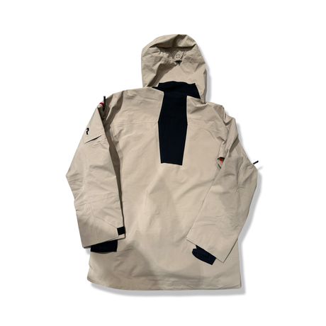 Baksidan av en beige Peak Performance Alpine Gore-Tex skaljacka för herr med huva och mörk stretchpanel, visad mot en vit bakgrund.