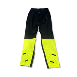 Svarta Gore Wear-regnbyxor med neongula benslut och Gore-Tex-märkning, fotograferade mot vit bakgrund.