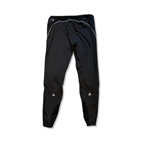 Baksidan av en svart träningsbyxa från Odlo logic windproof för dam, fotograferad mot en vit bakgrund.