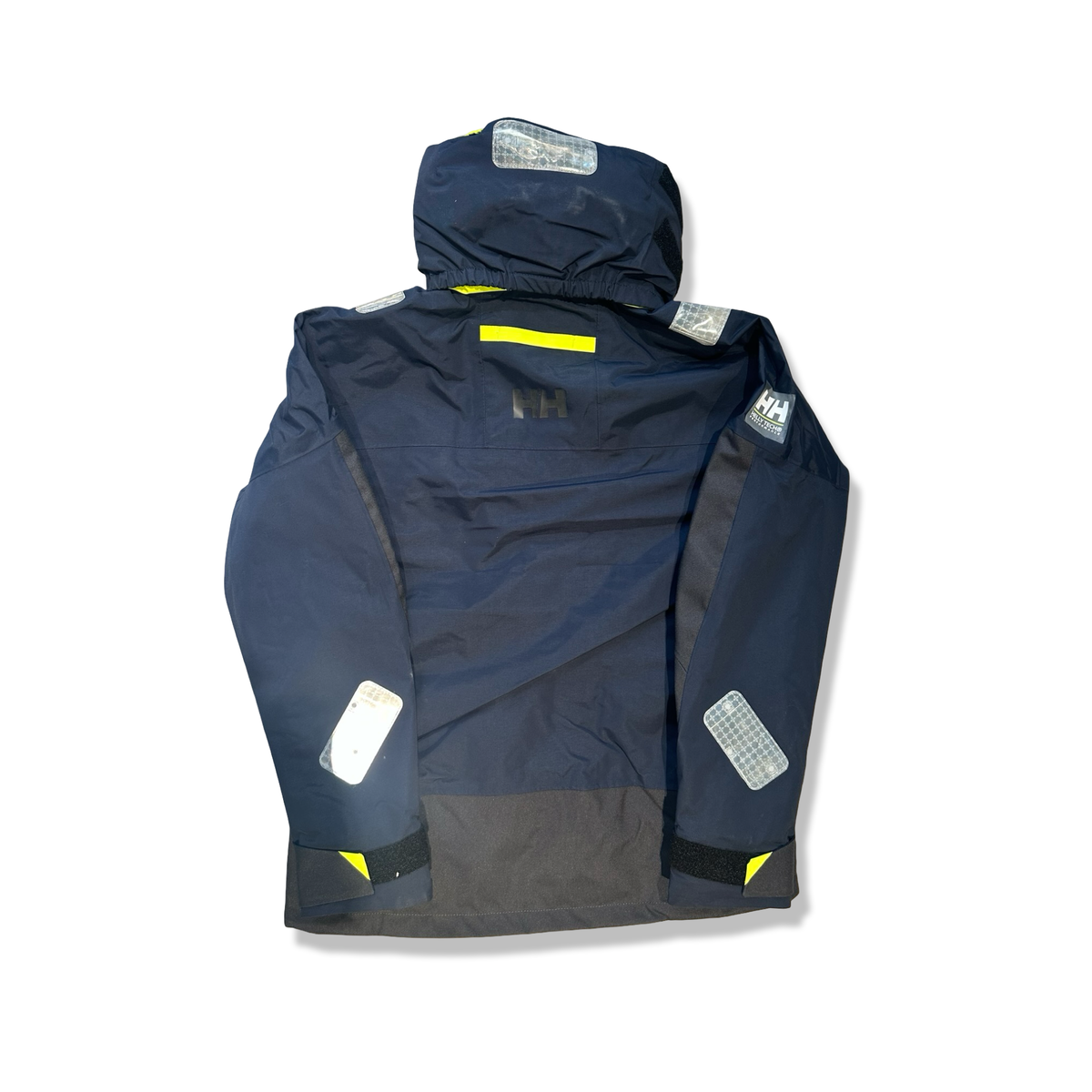 Baksidan av en mörkblå seglarjacka Helly Hansen Skagen offshore för dam med reflexdetaljer, fotograferad mot en vit bakgrund.